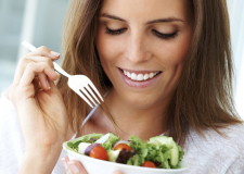 Close-up of young happy woman eating salad