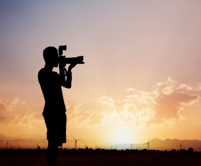 Man taking photos with camera at sunset