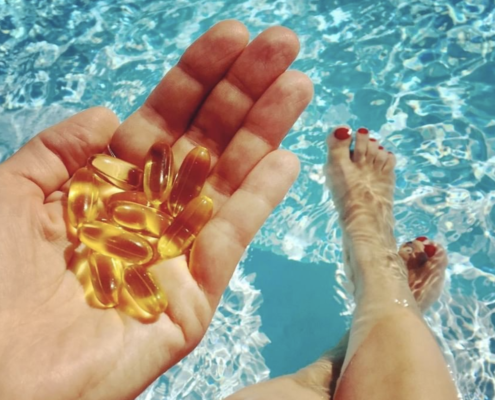 Hand Holding Fish Oil Supplements in Pool
