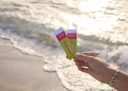 Hand holding two electrolyte support drink packets on the beach