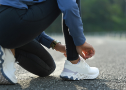 Woman crouched down tying athletic shoes getting ready for starting a jogging routine