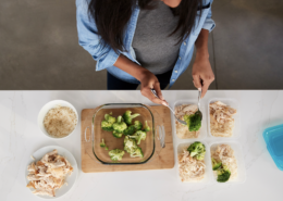 top down view of woman meal prepping for the week, broccoli and rice are included