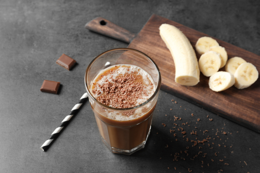 Glass with chocolate protein shake on table